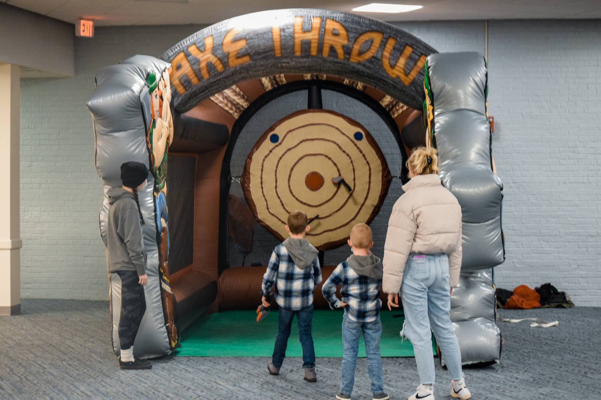 Kids throwing inflatable axes at inflatable target as others watch